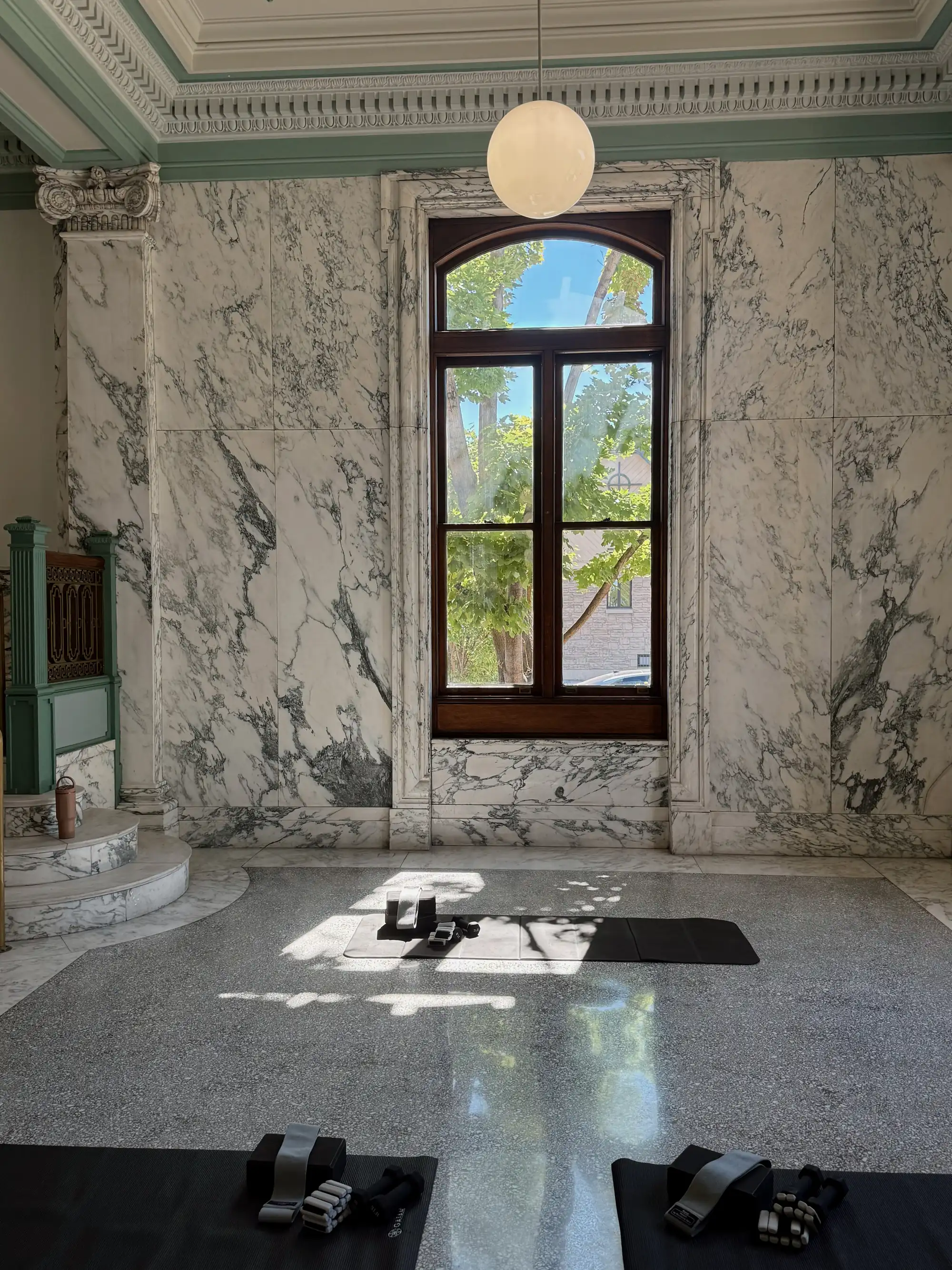 Mats laid out in the sunlit marble hall before class